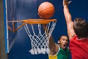 Man dunking basketball over defender